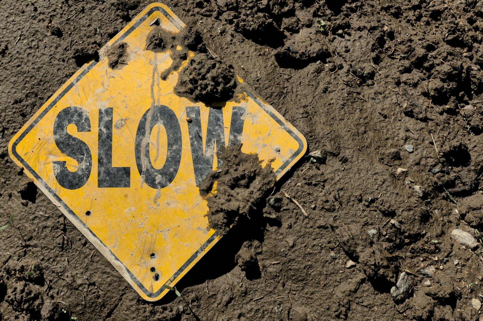 WordPress Wartung: Performance-Probleme erkennen und Nutzererfahrung verbessern Beschmutztes „SLOW“-Schild liegt im Matsch – Symbolbild für wordpress wartung, Performance-Probleme und deren Einfluss auf die Nutzererfahrung von Unternehmenswebsites.