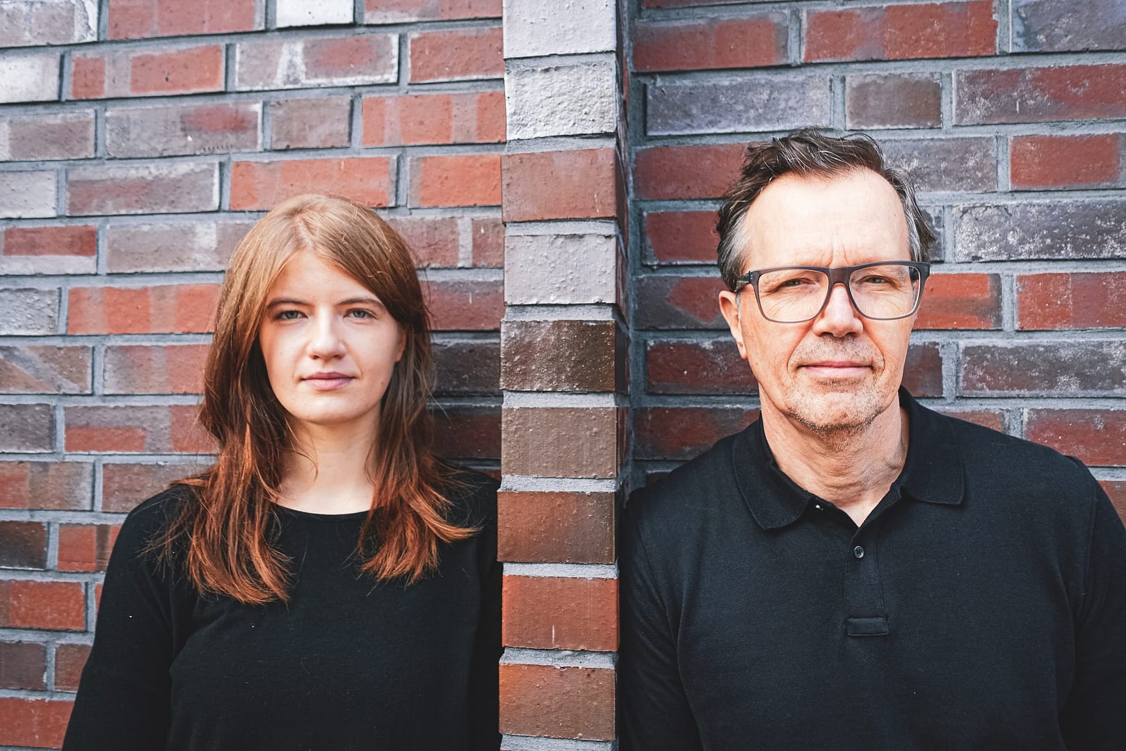 Zwei Teammitglieder von maxxed stehen nebeneinander vor einer Backsteinwand – Symbolbild für den Bereich „über uns maxxed“ und ein persönliches, partnerschaftliches Miteinander.