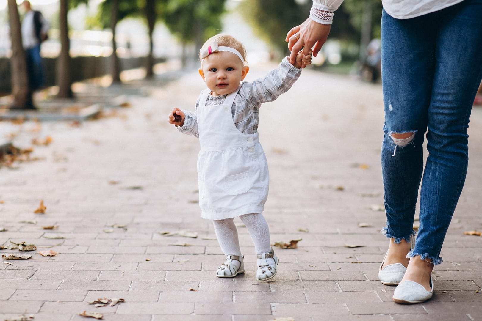 Little girl holding mother's hand in park
