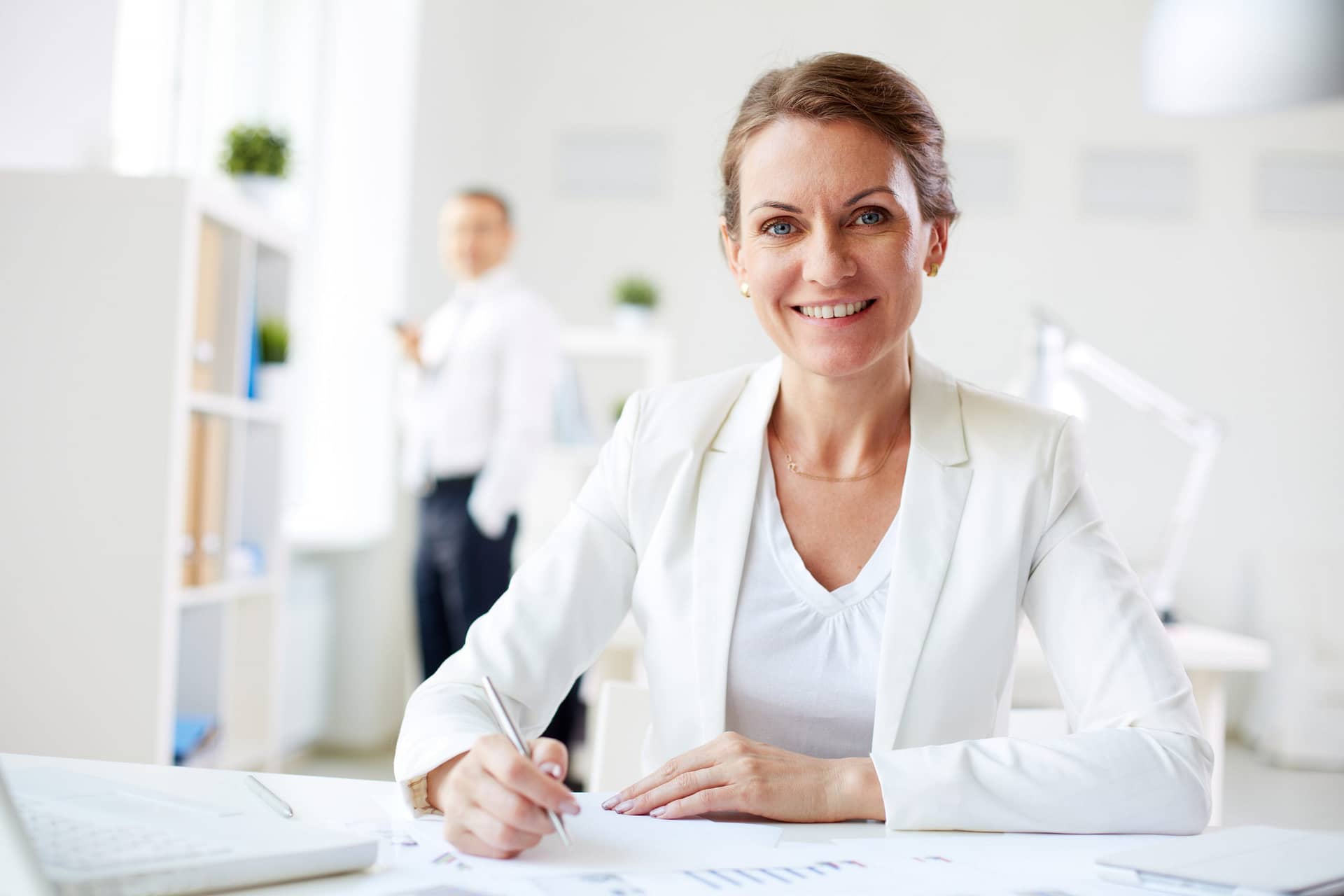 Geschäftsfrau in weißem Blazer arbeitet an Dokumenten im modernen Büro und bietet B2b Content Services an